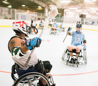 Adults playing a match of wheelchair lacrosse.