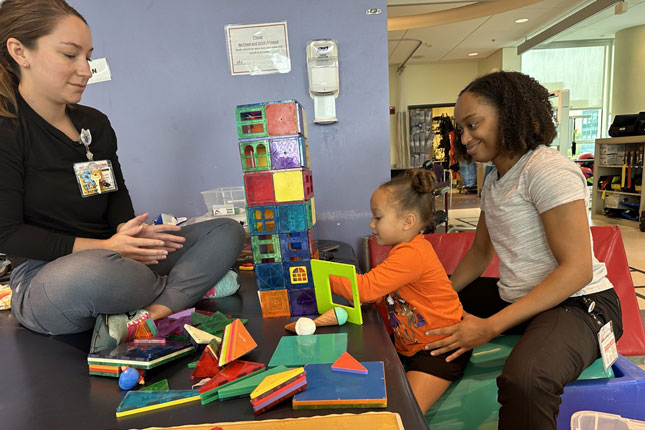 Two Child Life Specialists play with a young patient.