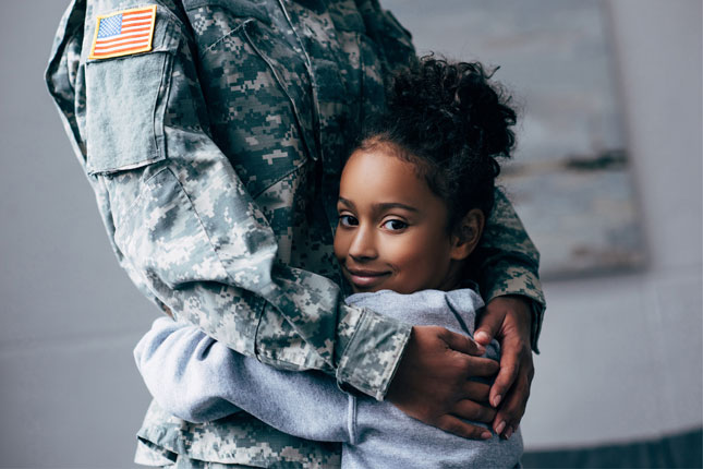 A little girl hugs a soldier.