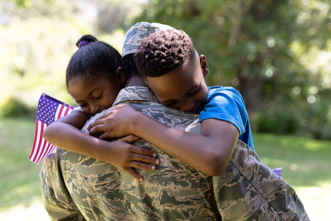 Stock image of a soldier embracing his daughter and son.
