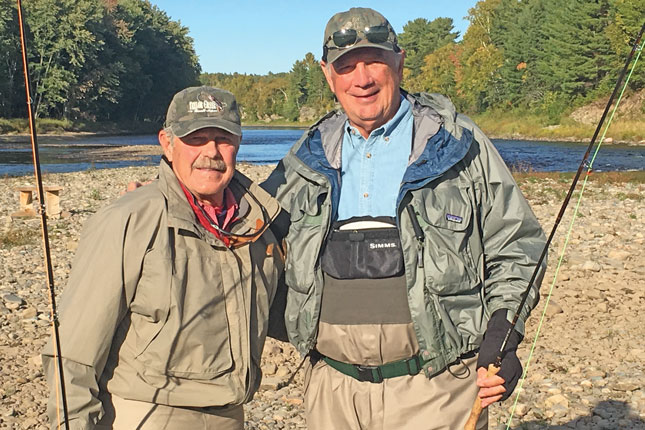Mike Batza, Jr. and Earl Linehan stand next to each other holding fishing rods.