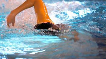 A swimmer in a pool, mid stroke.