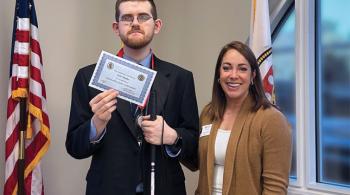 A young man holding a certificate and a woman stand next to each other in a photo