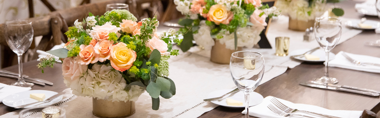 A photo of the table setup at Hats and Horses, featuring vases of flowers, plates, napkins, and glasses
