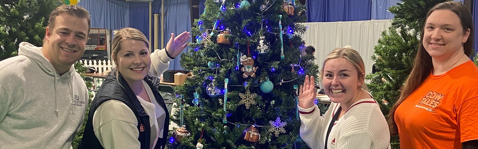 A group of people posing in front of a decorated holiday tree.