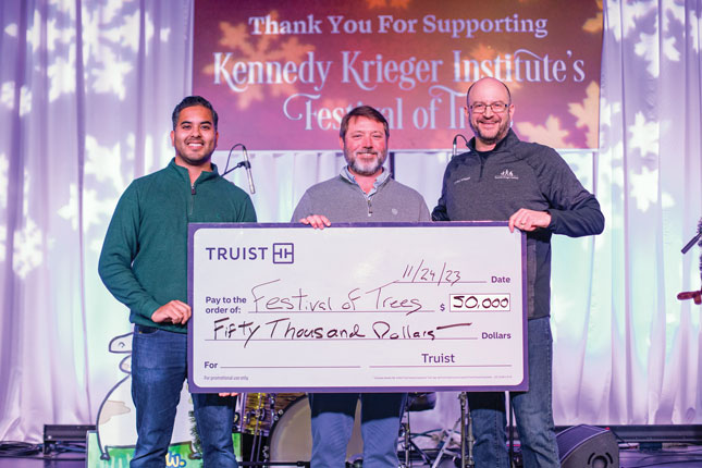 Three men smile as a ceremonial check is presented by Truist during Kennedy Krieger's Festival of Trees.