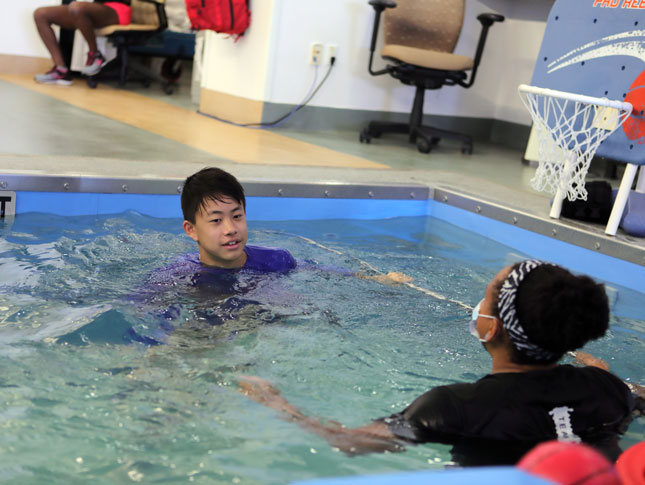 A teenage boy receives therapy in a swimming pool.