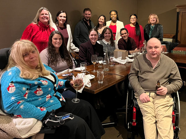 The MCDD team gathers around a table at their holiday party.