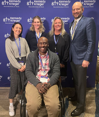 Kristine Nellenbach, Tracy Waller, Maureen van Stone , Kennedy Krieger president and CEO Dr. Brad Schlaggar and Chris Mason-Hale at the Neurodiversity in the Workplace conference. Mason-Hale is sitting in his mobility device as the others stand behind him.