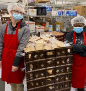 Two workers stand on either side of a bread cart.