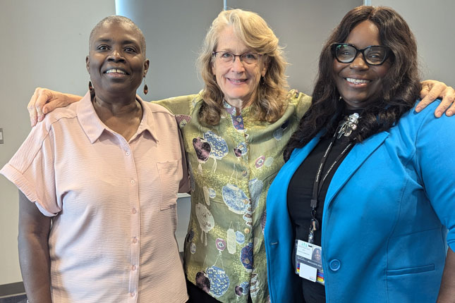 Three women wearing professional attire stand and for a group photo.