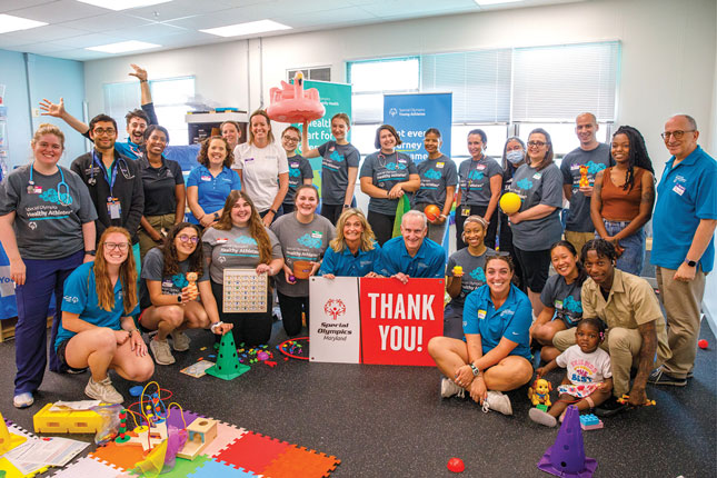 A large group of people pose around a read and white Special Olympics of Maryland sign that reads Thank You!