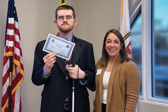 A young man holding a certificate and a woman stand next to each other in a photo 