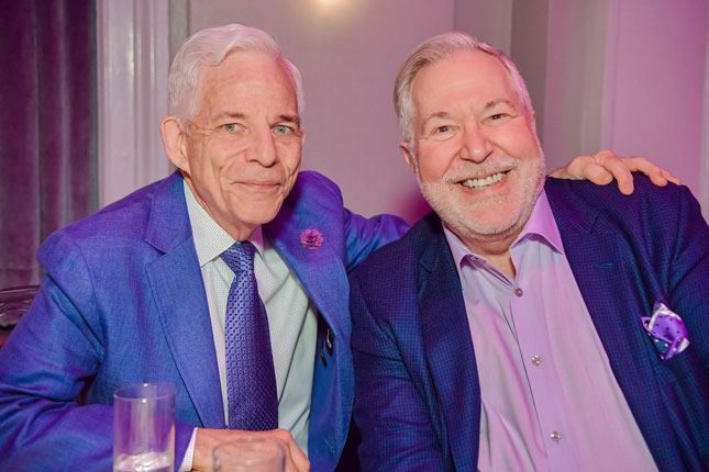 Patrick and Howard smile while sitting at a banquet table.