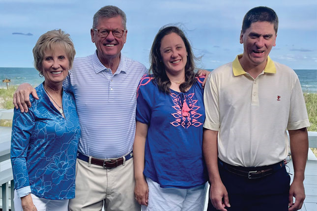 The Lewis family poses for a photo outside, with a beach in the background.