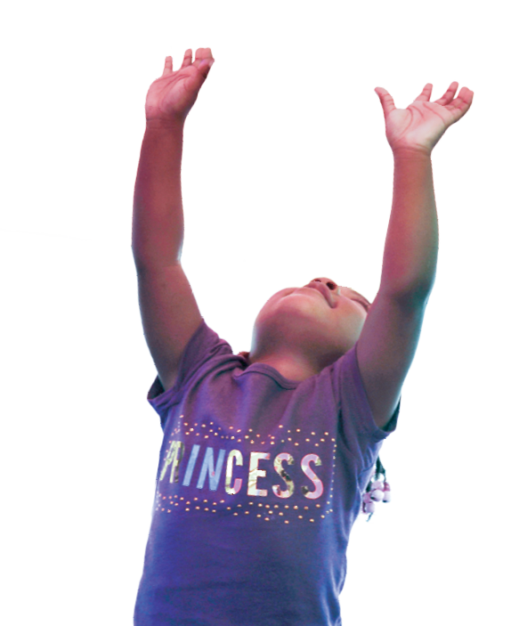 A young girl looks up and holds her hands in the air.