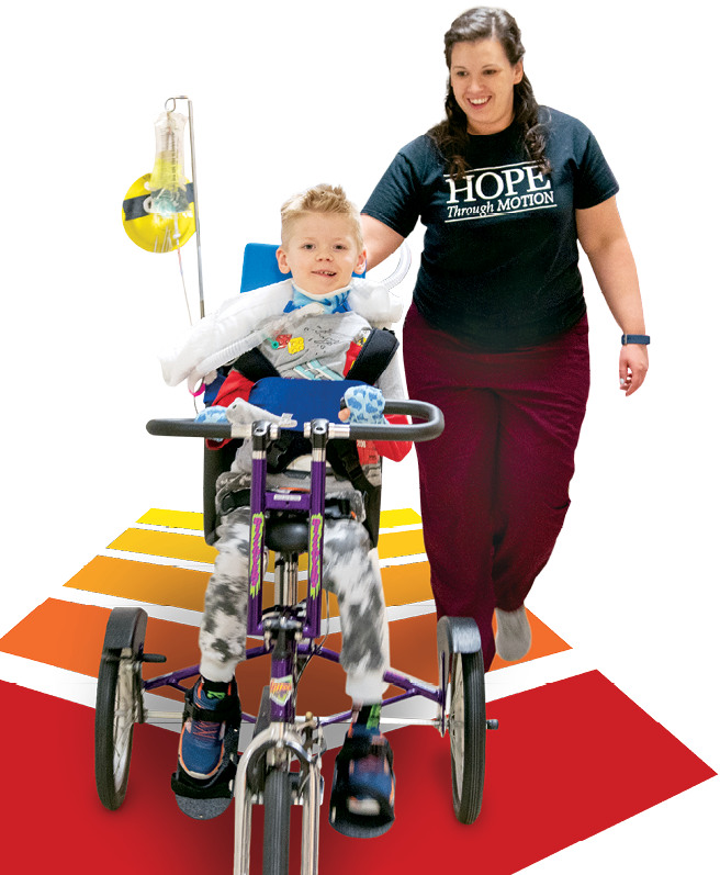 A photo of Geuko riding a tricycle with physical therapist Dr. Courtney Porter.