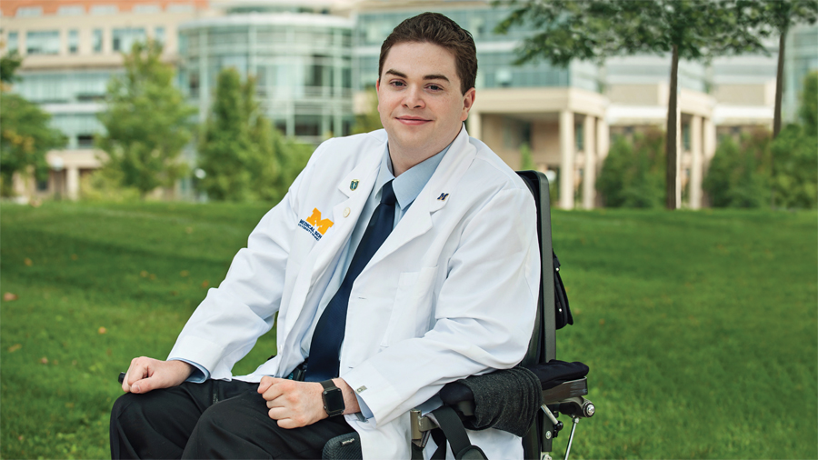 Chris Connolly poses wearing his University of Michigan Medical School white coat.