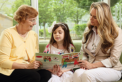 Kat reads a book with educational specialist Patty Porter, left, and her mom, Sandy.