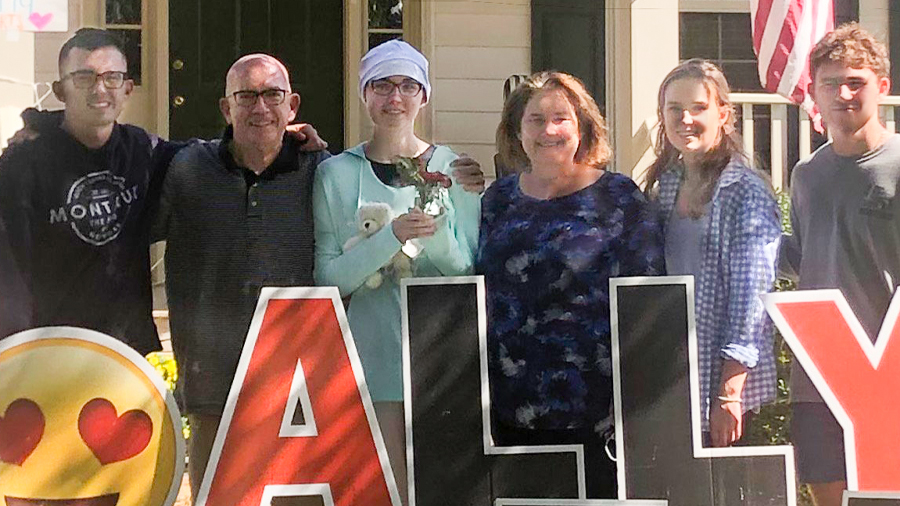 Ally (left of center) with her parents, John and Catherine, and siblings Jack, Katie and Patrick. They are standing behind red and black letters that spell Ally.