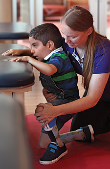 At Kennedy Krieger’s outpatient center, physical therapist Brittany Hornby helps Karam practice standing from a kneeling position.