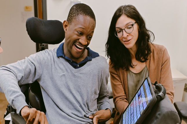 A patient uses a tablet with the assistance of a speech-language pathologist.