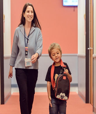 A patient and SLP smile while walking down a hallway.
