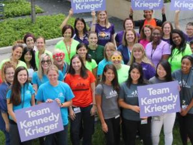 A group of Kennedy Krieger employees, wearing Kennedy Krieger shirts and holding signs that read, "Team Kennedy Krieger"