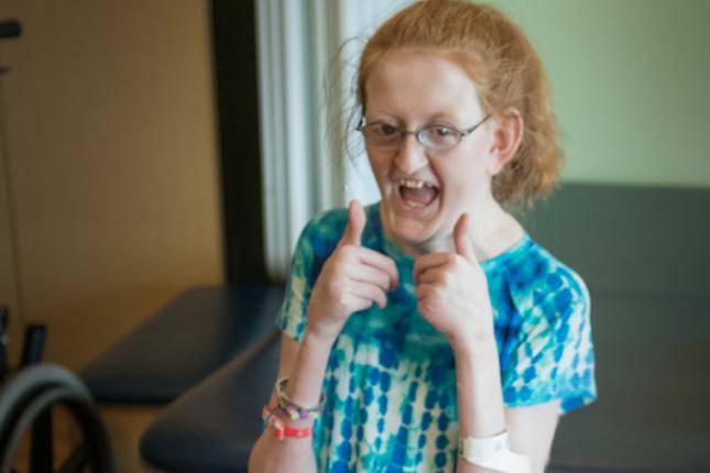 A photo of Ellie, a Kennedy Krieger patient, giving two thumbs up to the camera