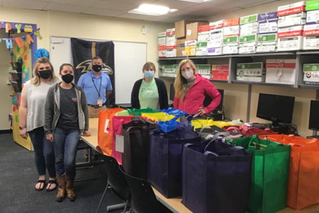 Kennedy Krieger staff members stand behind bags that were packed as part of an Act for Kindness. 