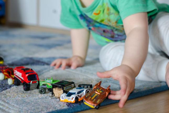 A small child plays with toy cars and trucks. 