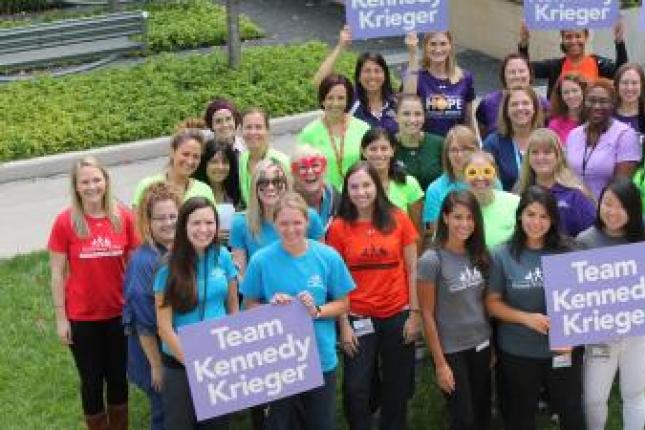 Un grupo de empleados de Kennedy Krieger que viste camisetas de Kennedy Krieger y sostiene carteles que dicen "Equipo Kennedy Krieger".