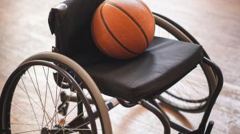 A photograph of a wheelchair with a basketball laying in the seat