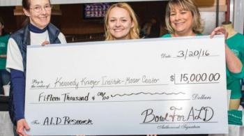Taylor holds a check that shows the amount of money she has raised to support ALD research at Kennedy Krieger