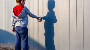 A boy with autism looks at his shadow.