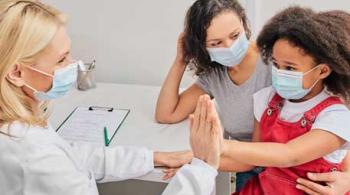 Un niño con su madre usando mascarillas protectoras en una cita con una médica que también está usando mascarilla.