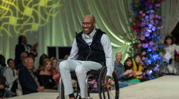 A man in a mobility device smiles on the runway during the 4th Annual Fall Fête. 
