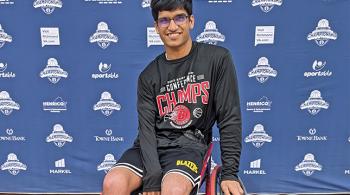 A young man in athletic clothing poses for the camera, sitting in a wheelchair.