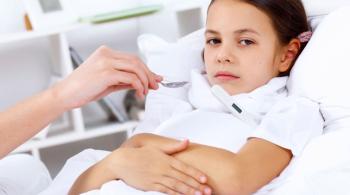 A young girl looks upset while lying in a hospital bed.