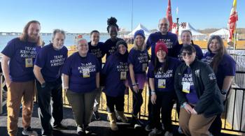 A group of Kennedy Krieger staff members smile while wearing purple Team Kennedy Krieger t-shirts.