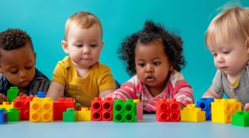 Cuatro niños jugando con bloques coloridos sentados en una mesa.