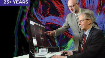 Two men in business suits work at a computer, which displays a colorful MRI image of a human brain.