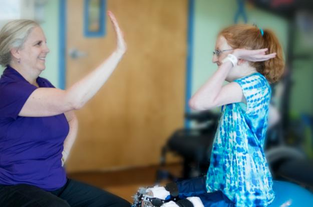 Kennedy Krieger patient Ellie high-fives a therapist