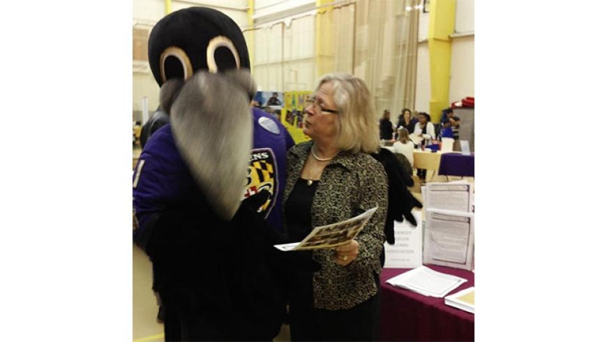A woman poses for a photo with Poe, the Baltimore Ravens mascot. 