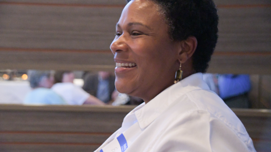 A profile of a woman wearing a white shirt and smiling. 